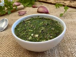 Chimichurri argentino casero en un tazón blanco con ajo y perejil fresco